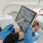 Dentist showing dental x-ray on tablet to patient in a modern clinic setting.