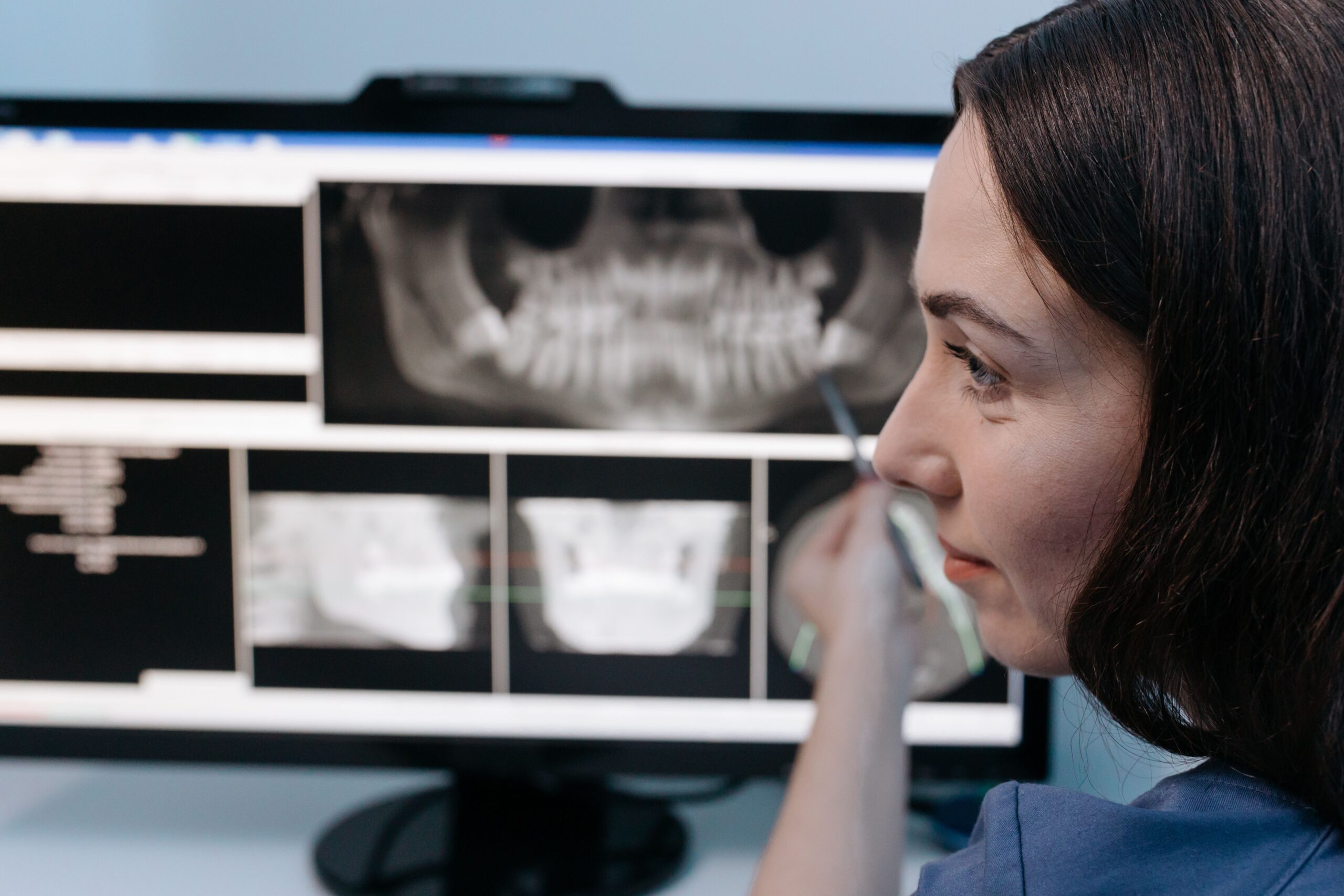 Our Services Female dentist reviewing digital dental x-rays on a computer screen in a clinic setting.