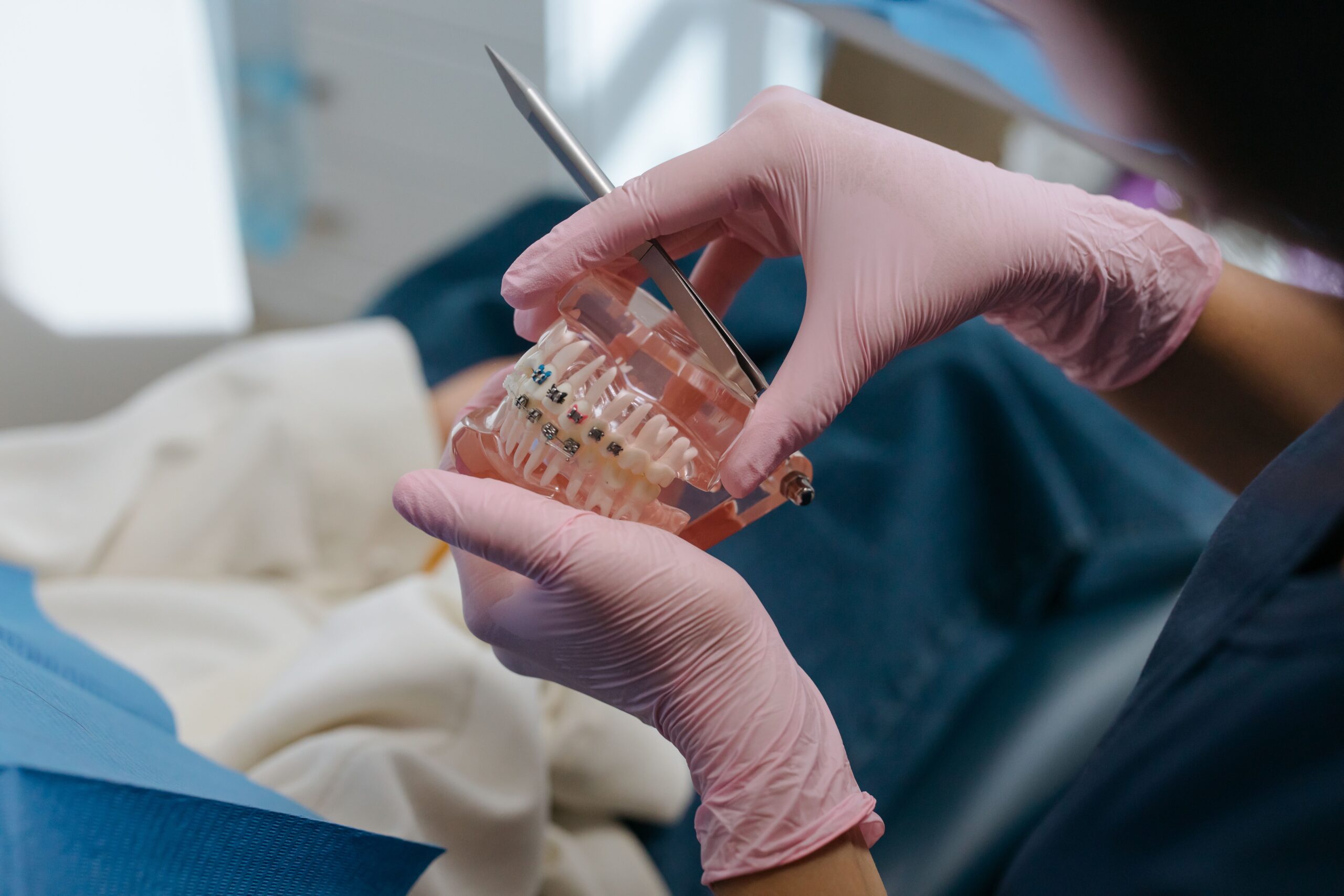 Our Services Close-up of a dental professional using tools on a teeth model with braces.
