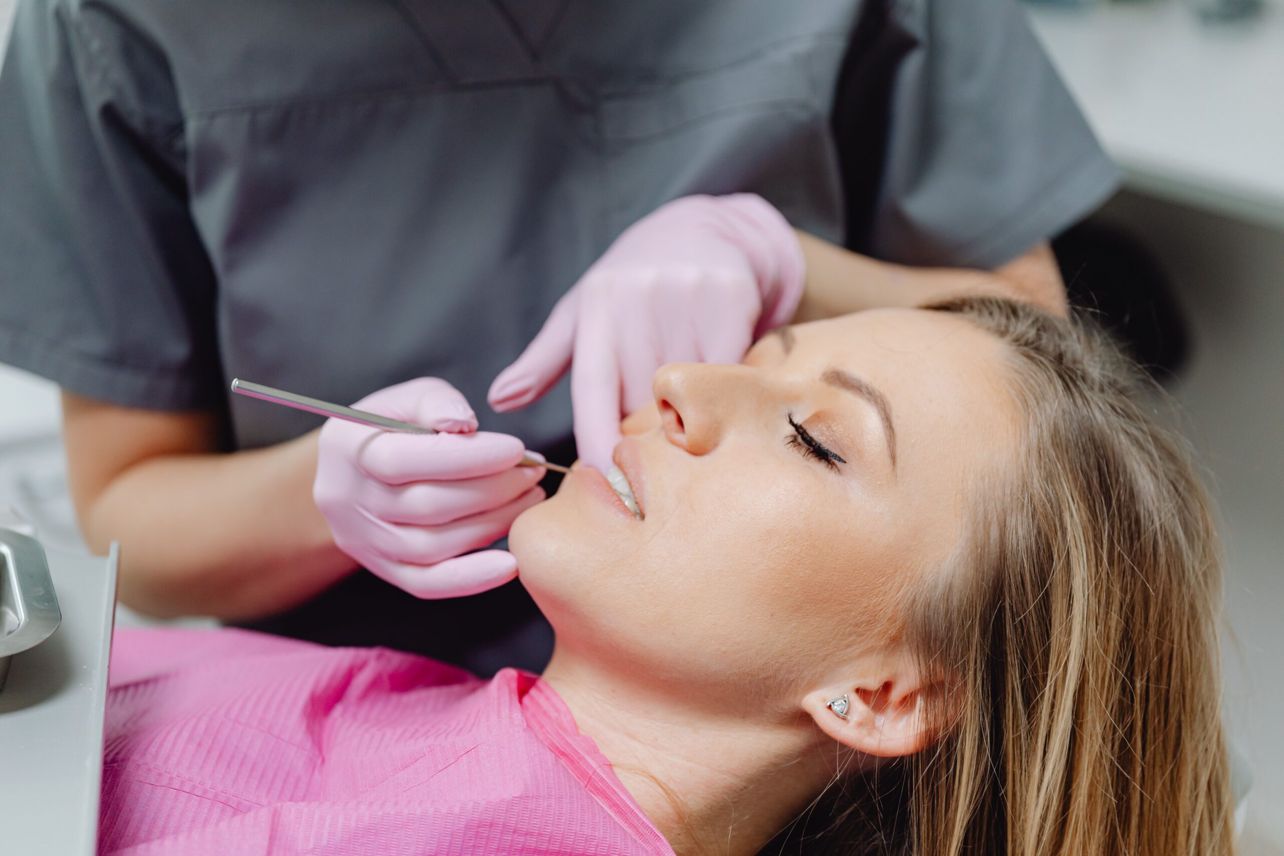 Our Services A female patient receives a dental examination by a dentist in a clinic.