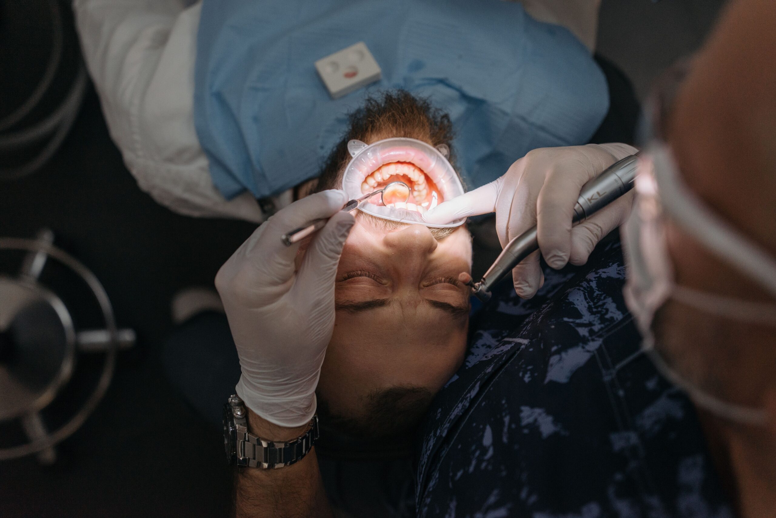 Our Services A dentist performing a thorough dental examination on an adult male patient in a clinic.