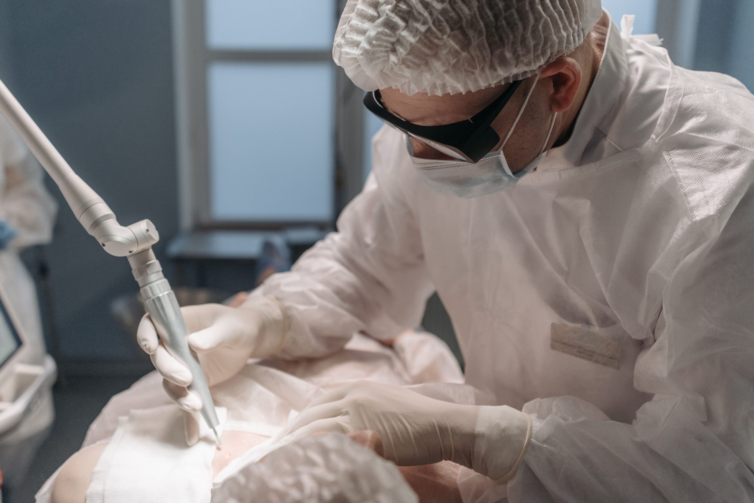 Our Services A focused surgeon performs laser surgery in a sterile operating room, emphasizing precision and care.