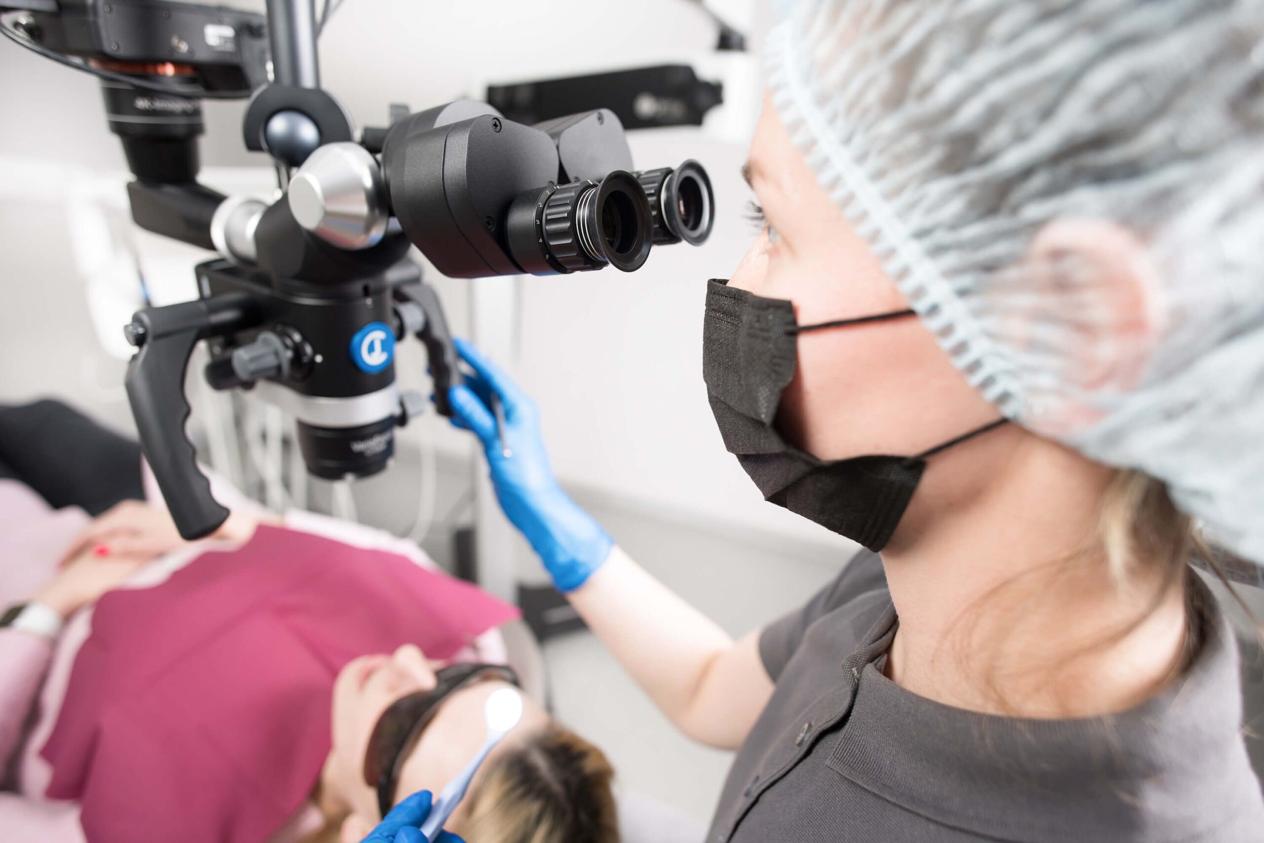 Our Services Dentist in clinic with microscope treating patient, Kyiv, Ukraine.