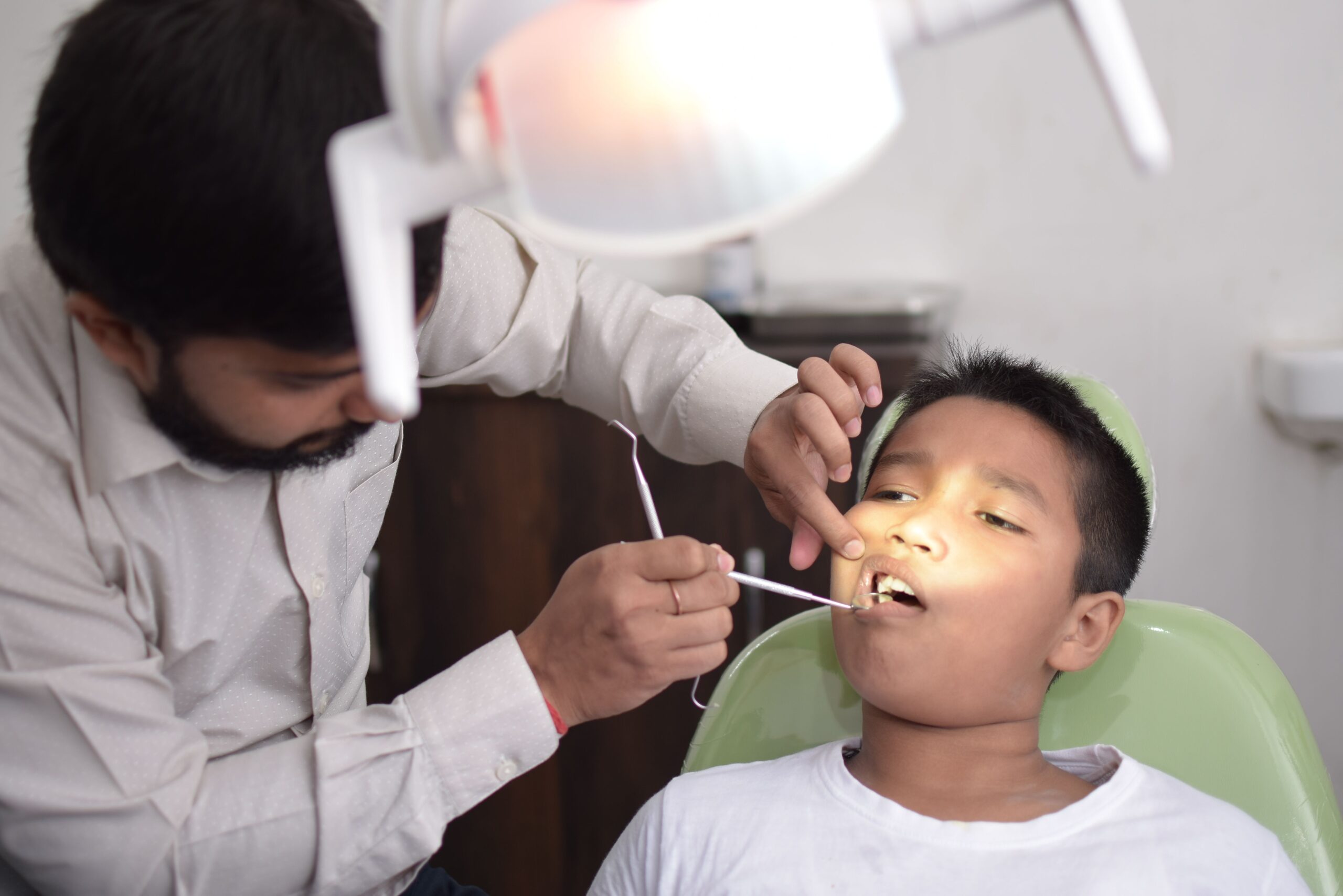Our Services A dentist checks a child's teeth in a well-lit dental clinic, focusing on oral care.